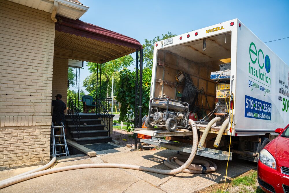 Eco Insulation truck on site with blown-in hoses running into the home